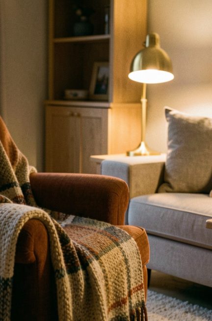 Salon chaleureux d’hiver avec lumière tamisée, plaid en tricot, coussins moelleux, bois clair et décoration cosy.